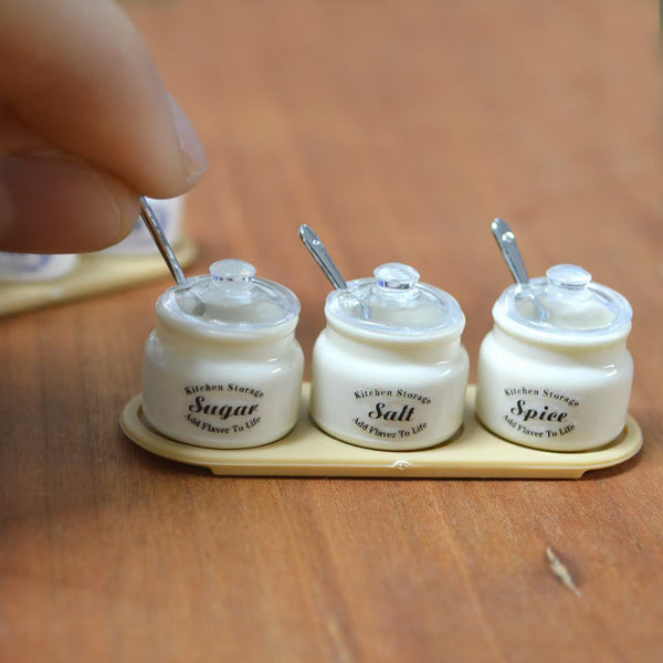 Hand holding miniature seasoning jar set with sugar salt spice labels