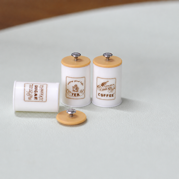 White three-piece miniature kitchen storage canister set with decorative labels