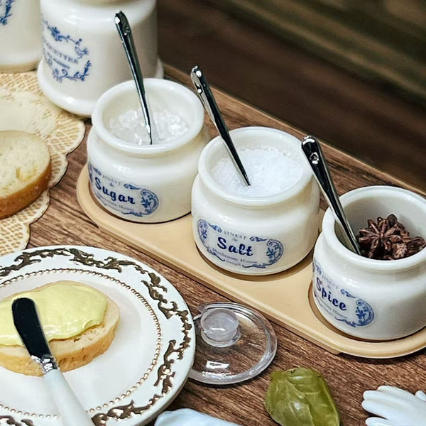 Miniature seasoning jars with spoons on a dollhouse table