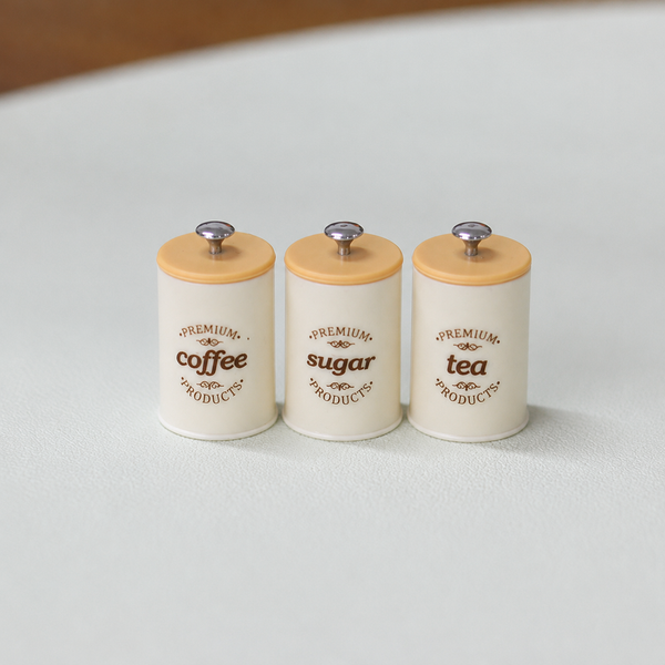 Gray three-piece miniature kitchen storage canister set with coffee, sugar, and tea labels